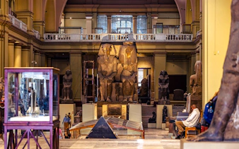 Grand Egyptian Museum interior with large ancient statues and display cases.