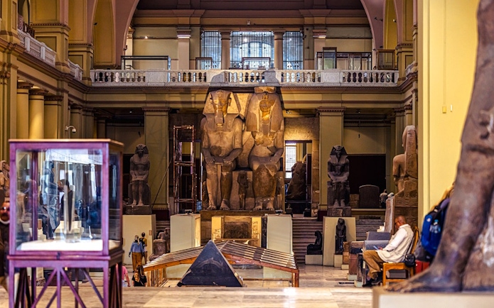 Grand Egyptian Museum interior with large ancient statues and display cases.