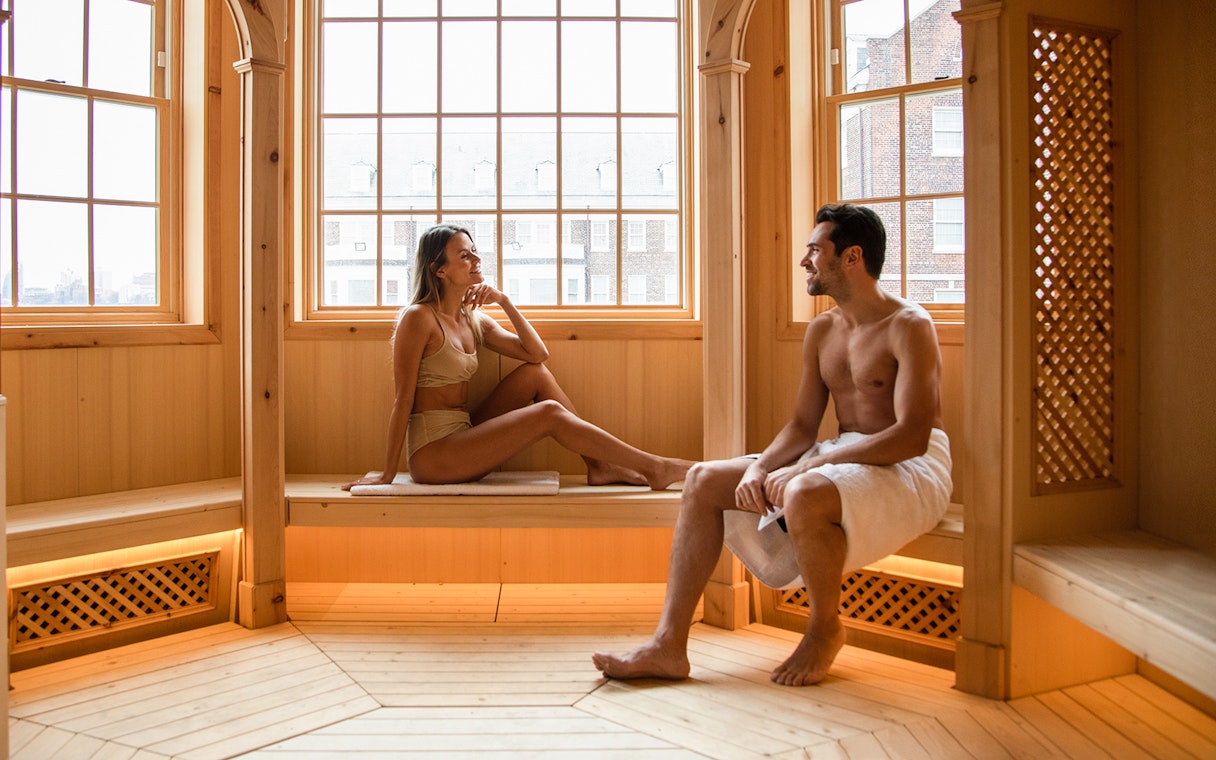 Couple relaxing in a wooden sauna at QC New York spa.