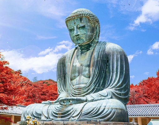 Kamakura Buddha statue surrounded by autumn foliage, Japan.