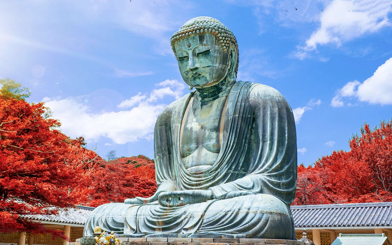 Kamakura Buddha statue surrounded by autumn foliage, Japan.