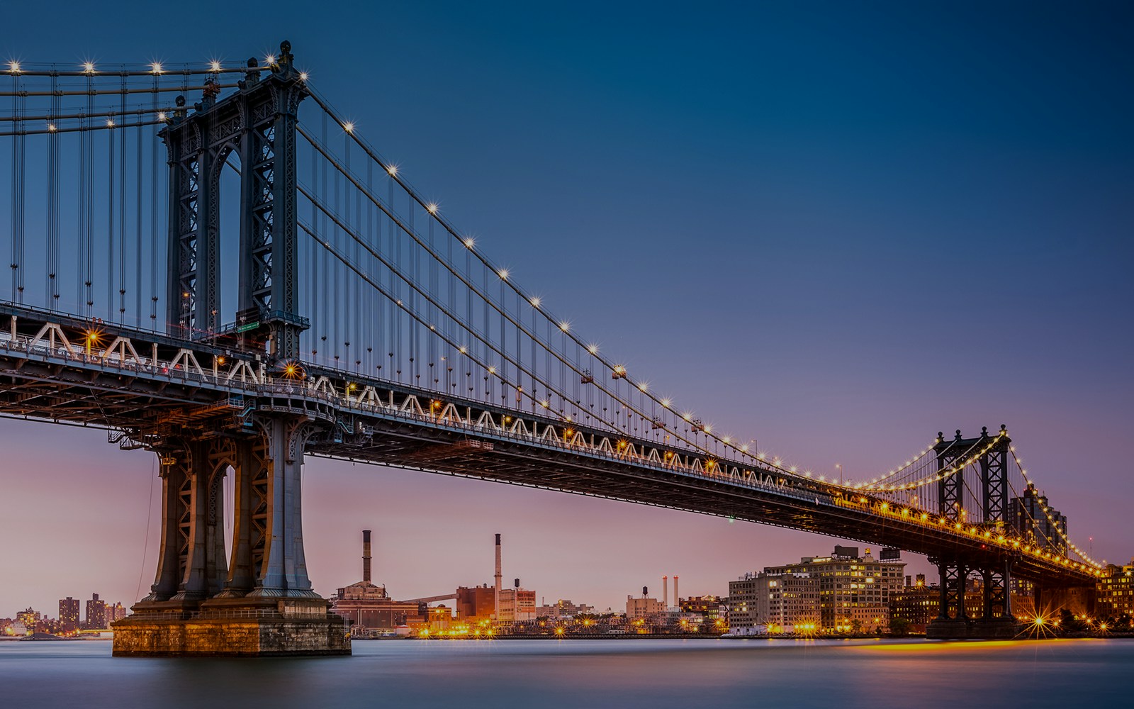 Manhattan Bridge at dusk with city skyline, New York City.