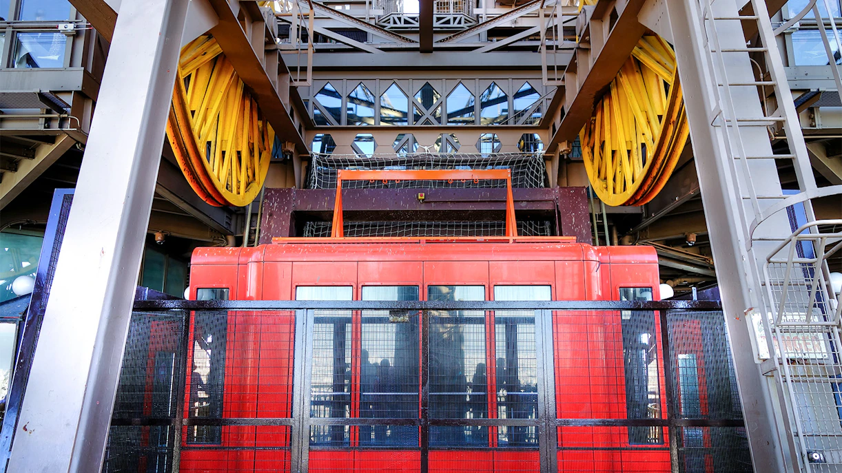 Eiffel Tower second floor elevator machinery with red lift and yellow pulleys.