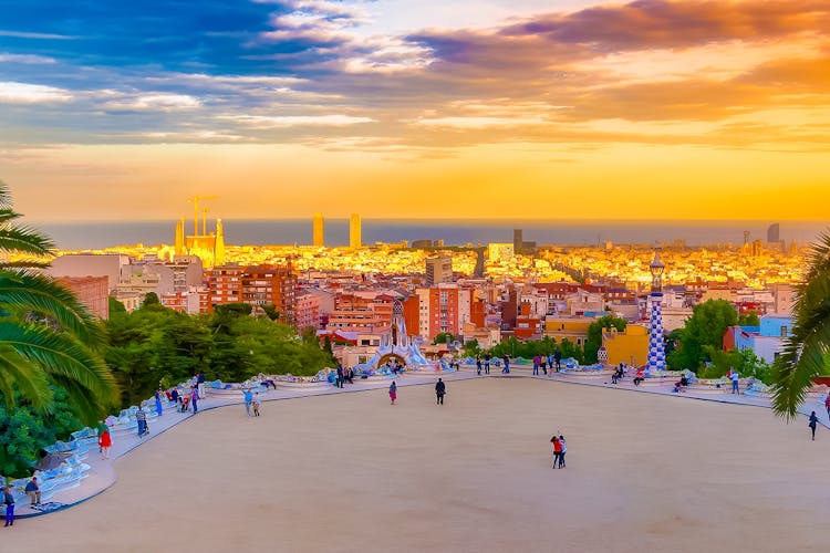Park Güell's colorful mosaic terrace overlooking Barcelona at sunset.