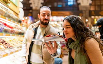 Tourist smelling dried fruits at Istanbul Spice Market Bazaar.