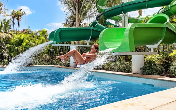 Person sliding down a green water slide at Baha Mar Waterpark, Nassau, Bahamas.