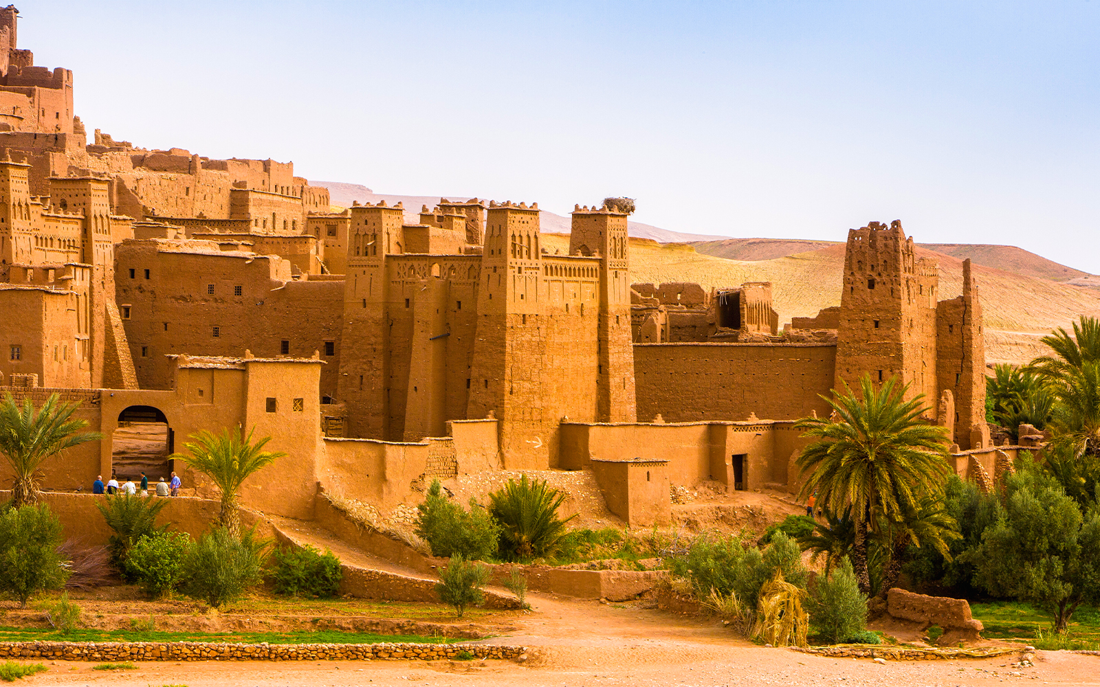 Ait Benhaddou village with traditional earthen buildings and palm trees in Morocco.