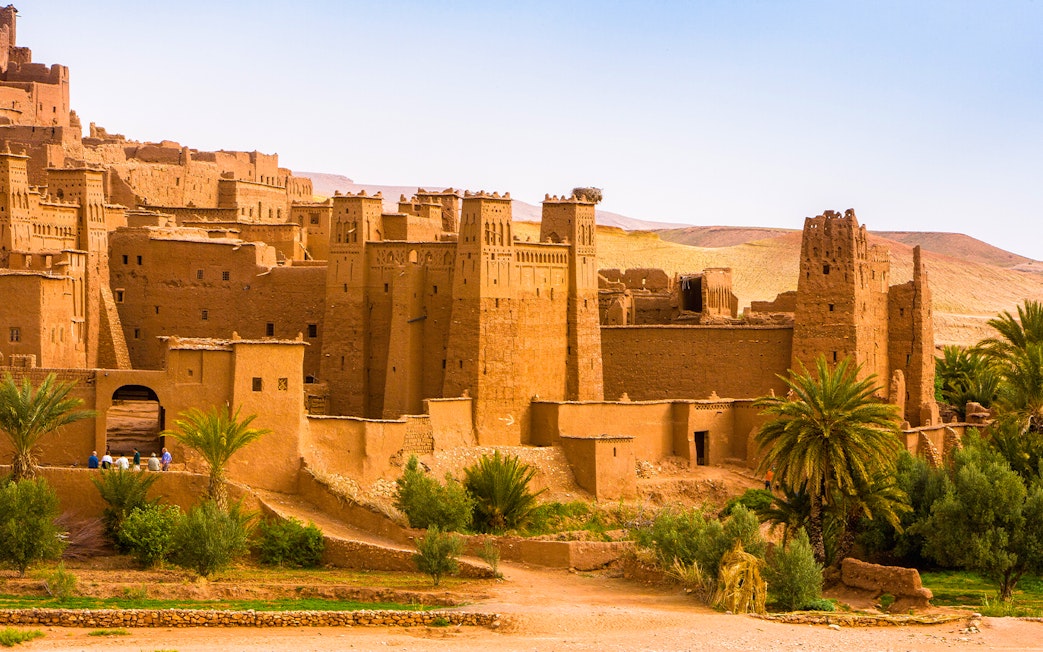 Ait Benhaddou village with traditional earthen buildings and palm trees in Morocco.