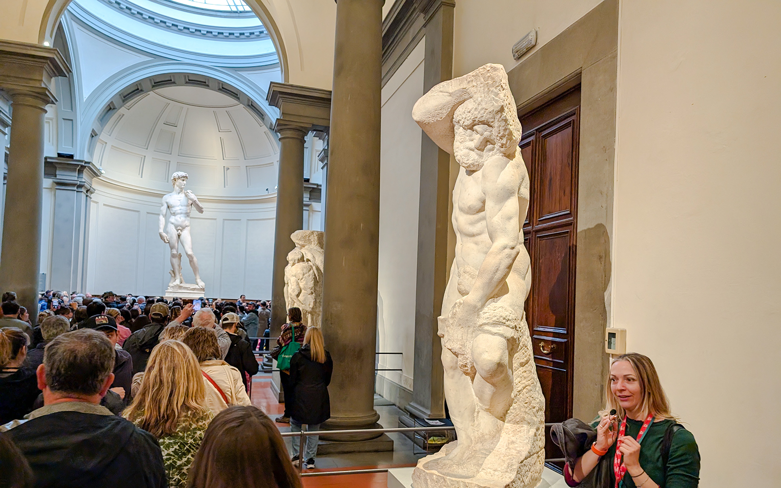 Bearded Slave sculpture in Accademia Gallery, Florence, with visitors nearby.