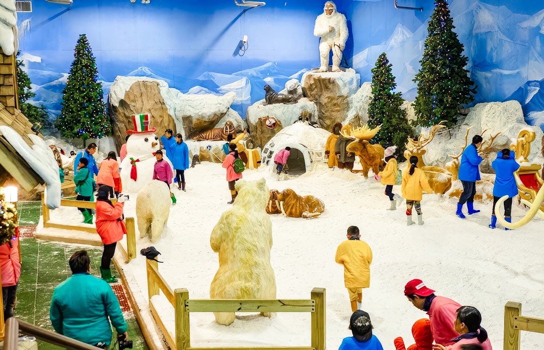 Visitors exploring Snow Town at Dreamworld Bangkok with snow sculptures and festive decorations.