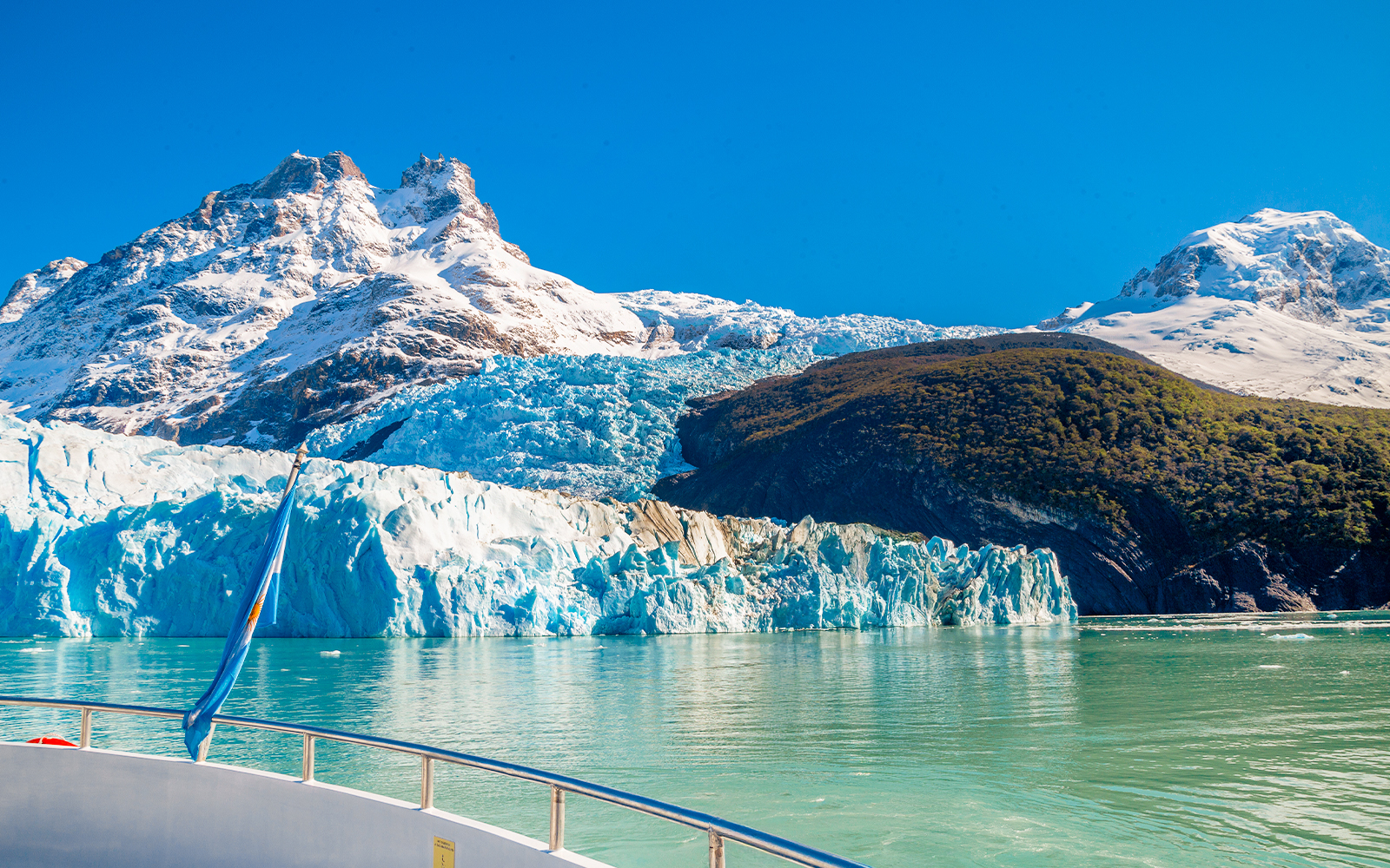 Boat approaching Spegazzini Glacier with snow-capped mountains in Los Glaciares National Park, Argentina.