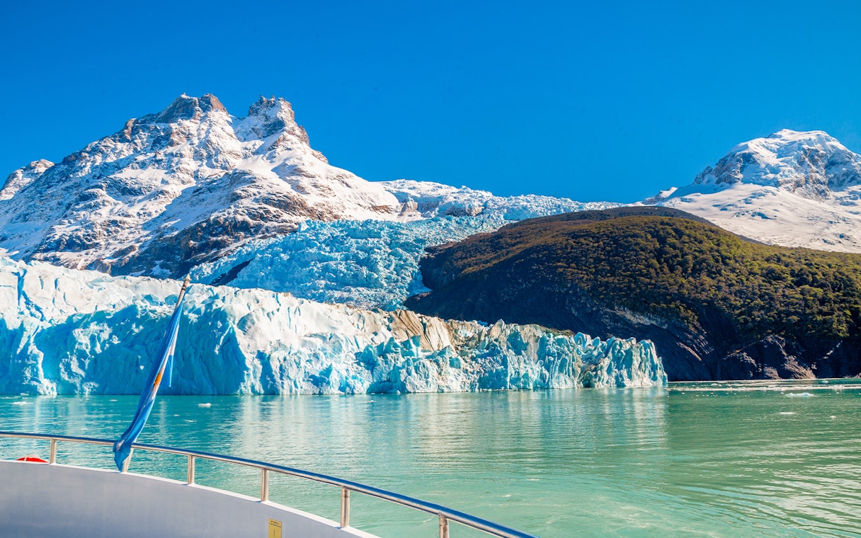 Boat approaching Spegazzini Glacier with snow-capped mountains in Los Glaciares National Park, Argentina.