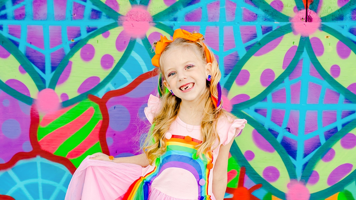 Girl smiling in front of a colorful geometric mural.