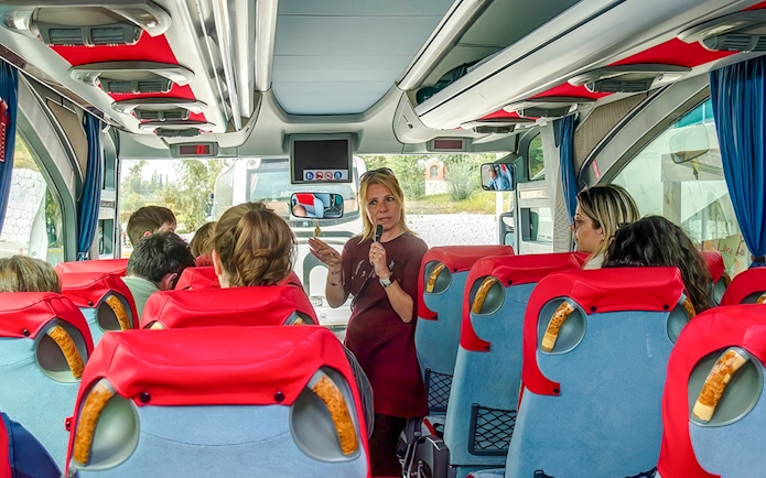 Tour guide speaking to guests on a bus during Ancient Mycenae & Nafplion Premium Tour.