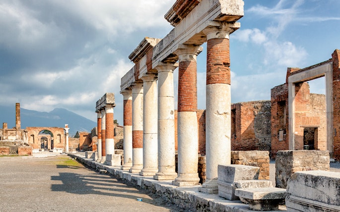 Eumachia building ruins in Pompeii with Mount Vesuvius in the background, Rome to Amalfi Coast day trip.