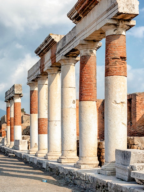 Eumachia building ruins in Pompeii with Mount Vesuvius in the background, Rome to Amalfi Coast day trip.
