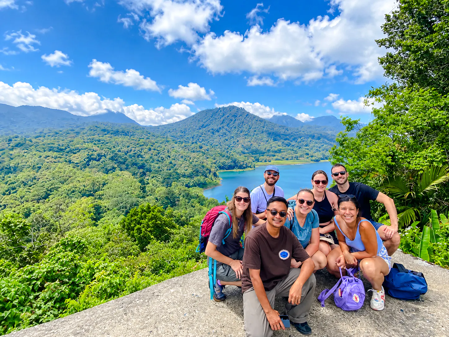 Group of tourists posing with view of Bali's Twin Lakes and lush forest.