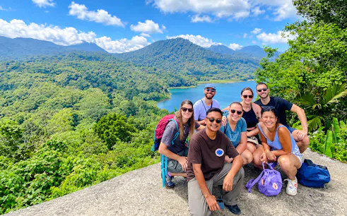 Group of tourists posing with view of Bali's Twin Lakes and lush forest.