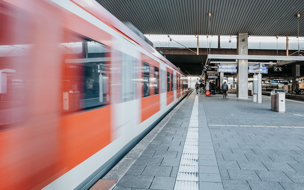 Train departing from a busy station platform with passengers nearby.
