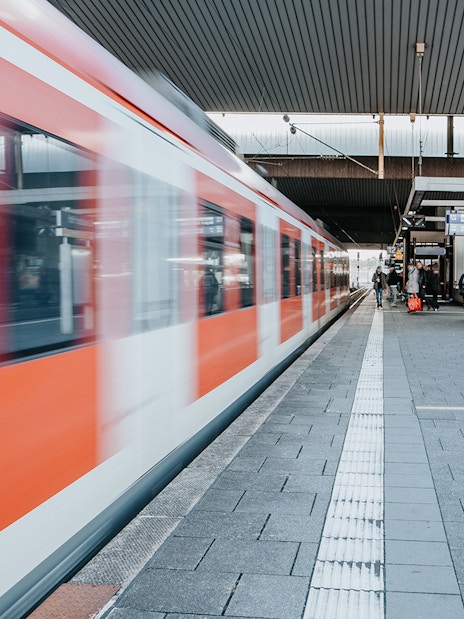 Train departing from a busy station platform with passengers nearby.