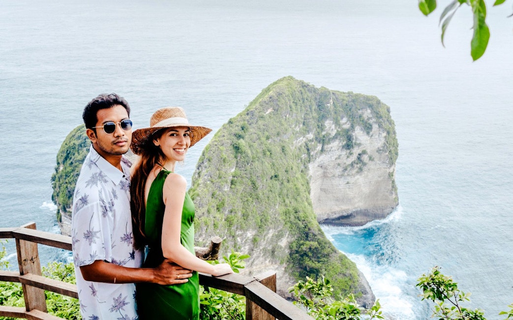 Couple enjoying the view of Kelingking Beach cliffs on West Nusa Penida Island tour.