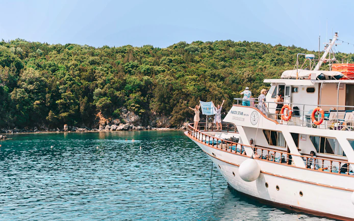 Cruise boat near lush coastline on Blue Lagoon & Papanikolis tour from Benitses/Lefkimmi.
