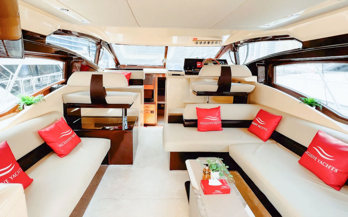 Seating area inside luxury yacht with plush sofas and red cushions.