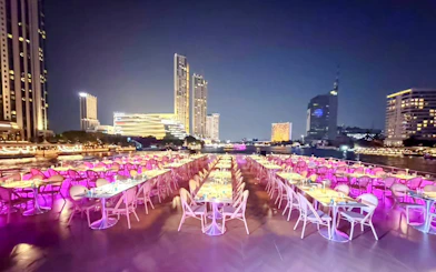 Upper deck dining with skyline views on Chao Phraya River dinner cruise in Bangkok.