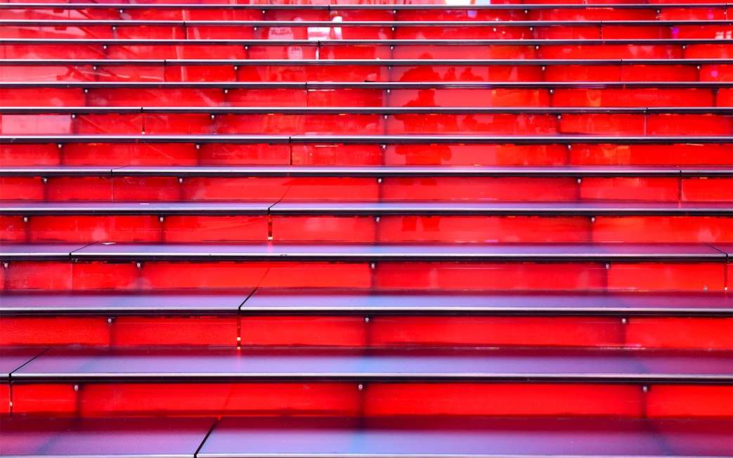 Red stairs at Times Square, NYC, leading up in a symmetrical row.