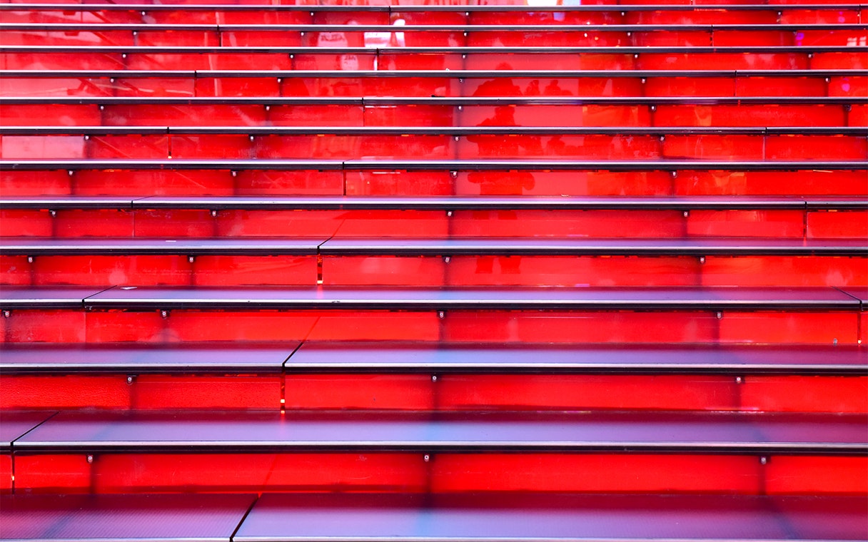 Red stairs at Times Square, NYC, leading up in a symmetrical row.