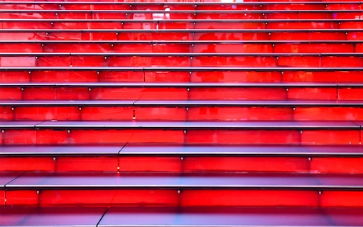 Red stairs at Times Square, NYC, leading up in a symmetrical row.