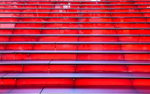 Red stairs at Times Square, NYC, leading up in a symmetrical row.