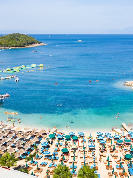 Ksamil Beach view with sun loungers, umbrellas, and clear blue water in Albania.