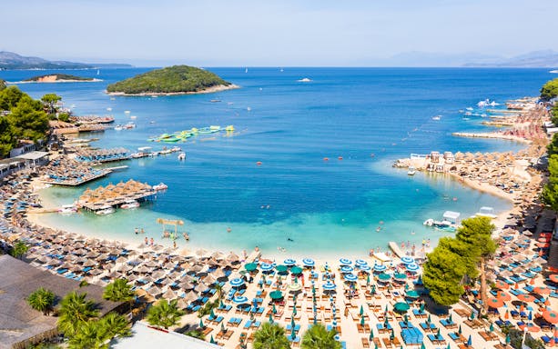Ksamil Beach view with sun loungers, umbrellas, and clear blue water in Albania.