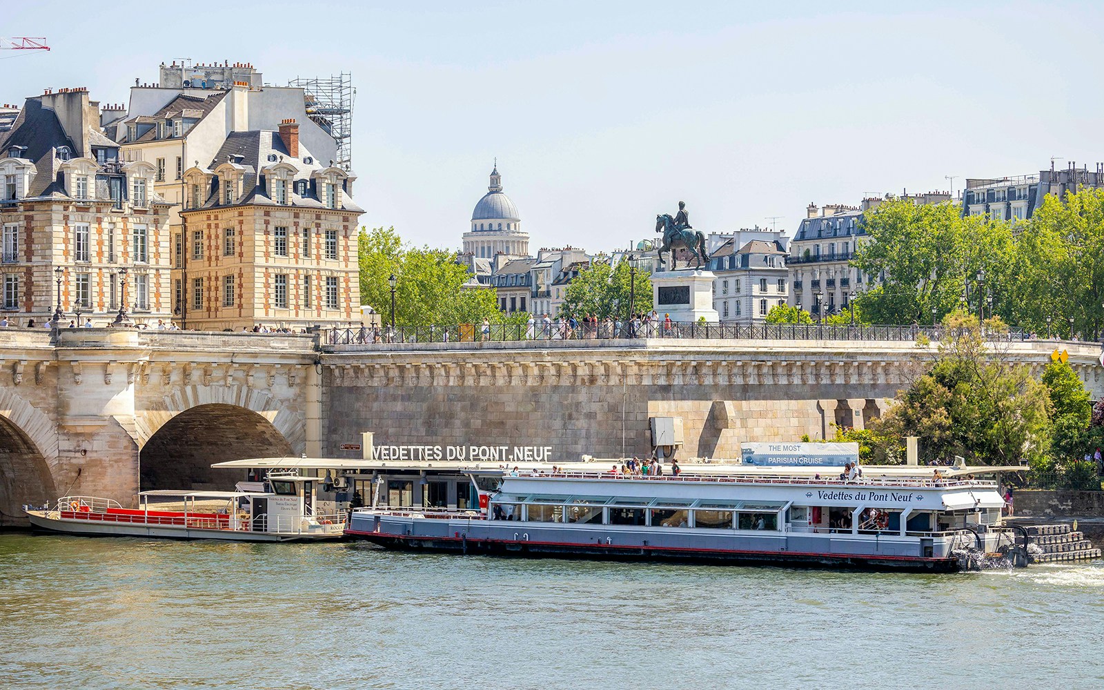 Seine River cruise boat docked at Paris boarding port with Eiffel Tower in background.