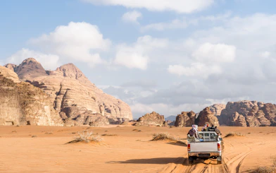Jeep driving through Wadi Rum desert landscape, Jordan.