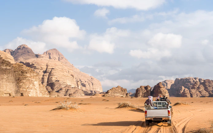 Jeep driving through Wadi Rum desert landscape, Jordan.