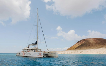 Catamaran sailing near La Graciosa Island with volcanic landscape in the background.