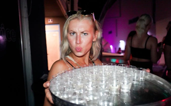 Person holding a tray of shot glasses at Split night boat party with live DJ.