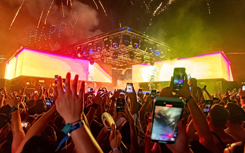 Crowd enjoying a vibrant night event at Atlas Beach Club with fireworks overhead.
