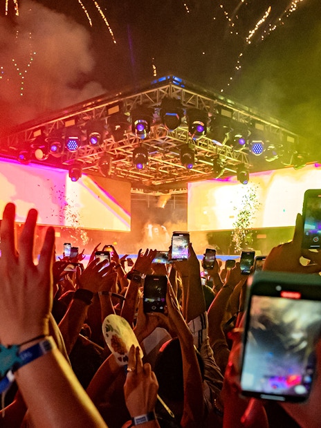 Crowd enjoying a vibrant night event at Atlas Beach Club with fireworks overhead.