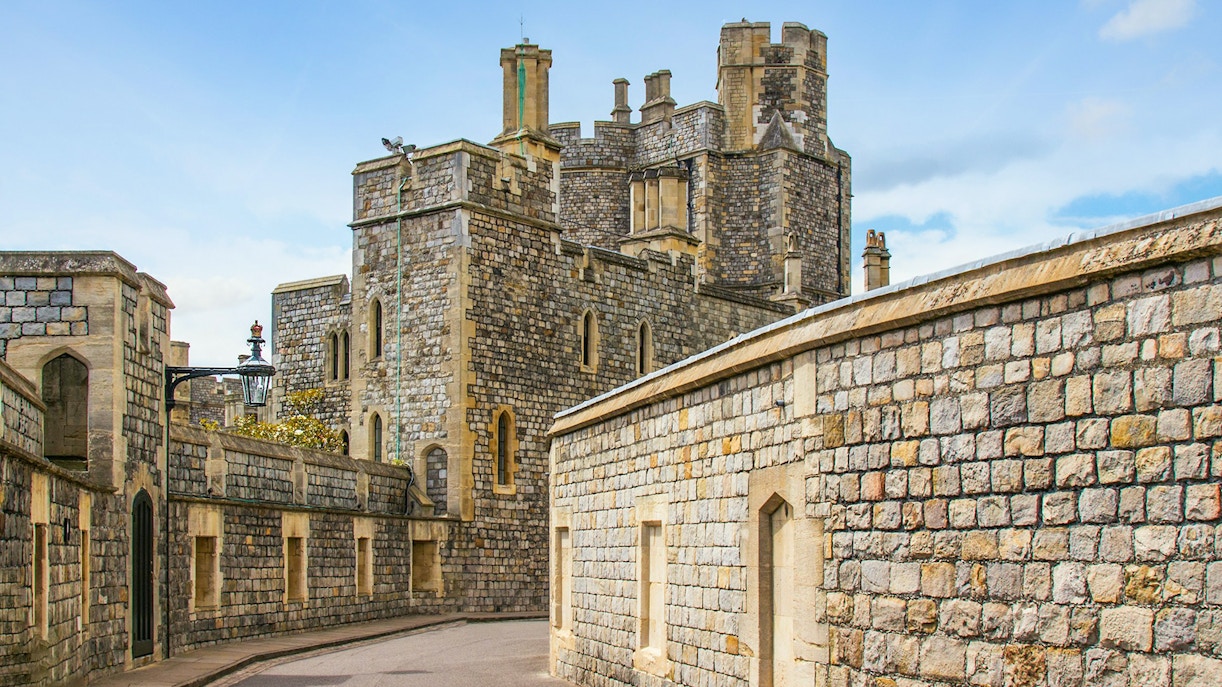 Windsor Castle stone walls and towers under a blue sky.