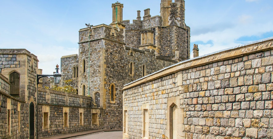 Windsor Castle stone walls and towers under a blue sky.