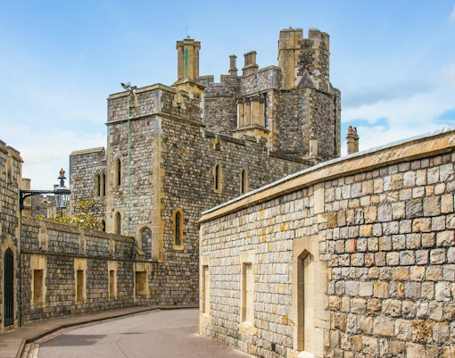 Windsor Castle stone walls and towers under a blue sky.