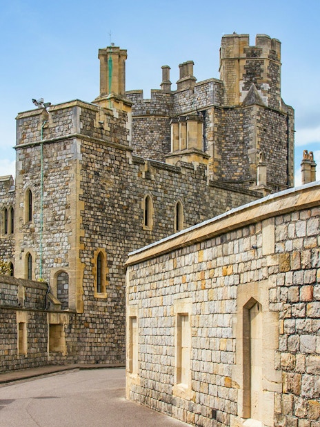 Windsor Castle stone walls and towers under a blue sky.