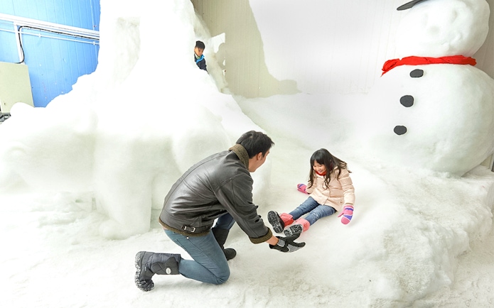 Child playing in snow with adult at Singapore Snow City.