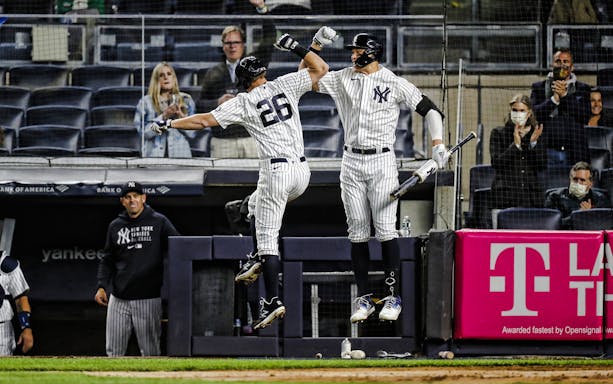 Yankees players celebrating a home run at Yankee Stadium.