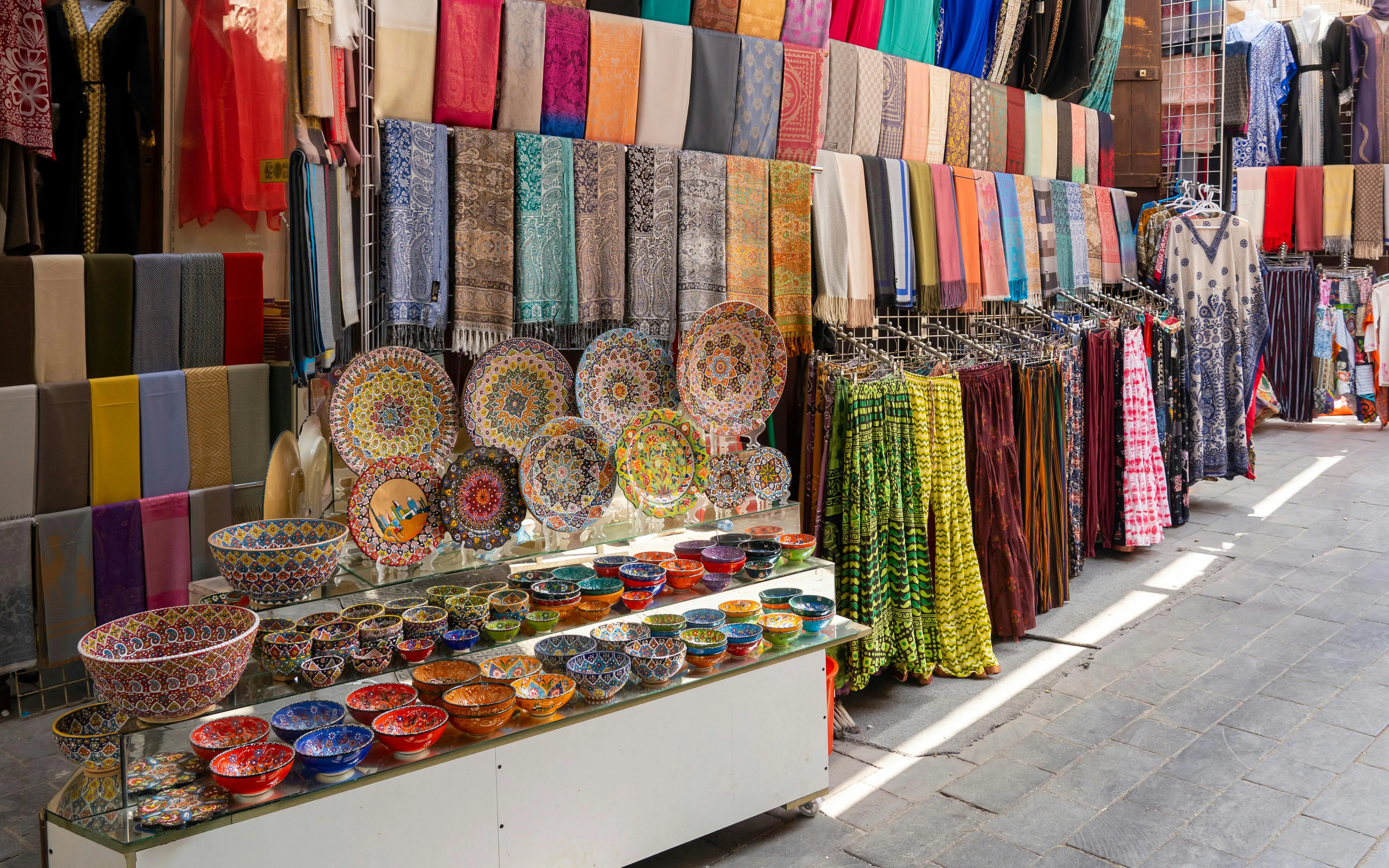 Colorful textiles and ceramics displayed at Dubai Textile Souk Market.