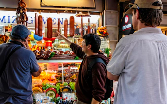 Tourists exploring a deli with hanging sausages on an Istanbul food tour.