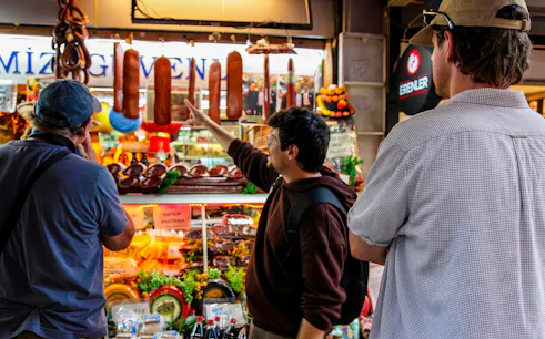 Tourists exploring a deli with hanging sausages on an Istanbul food tour.